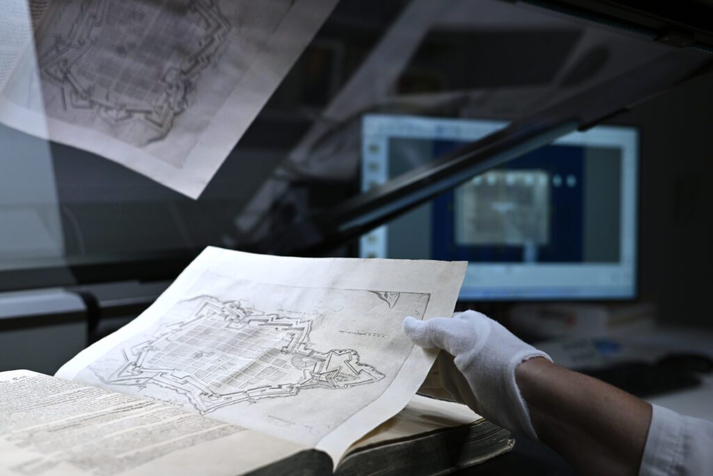 Member of the NSK Imaging and Digitisation Division scanning an item from NSK collections.