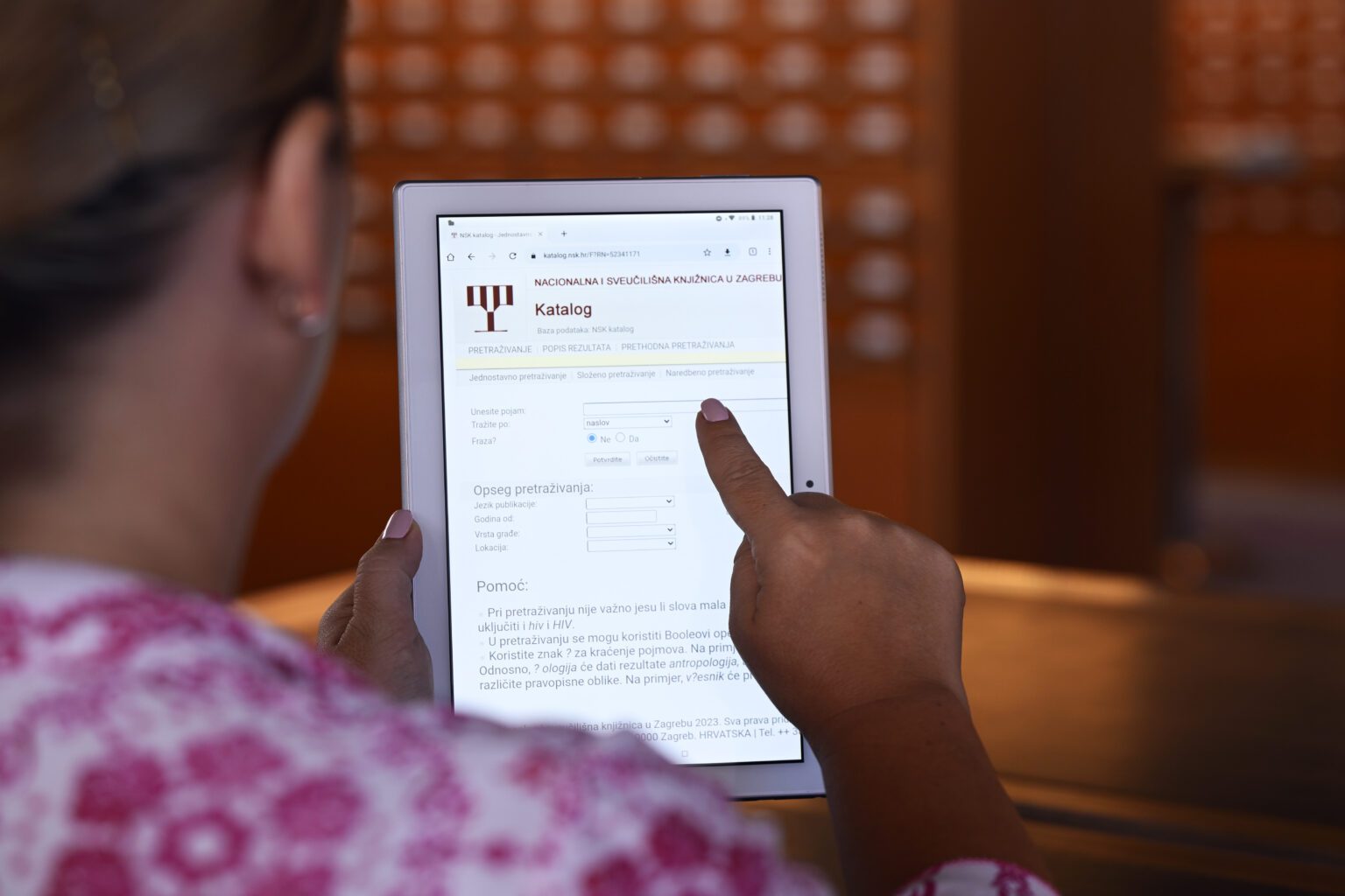 NSK Catalogue and NSK Integrated Library System to be briefly unavailable on 23 Jan 2024 Female person searching the Catalogue of the National and University Library in Zagreb using a tablet.