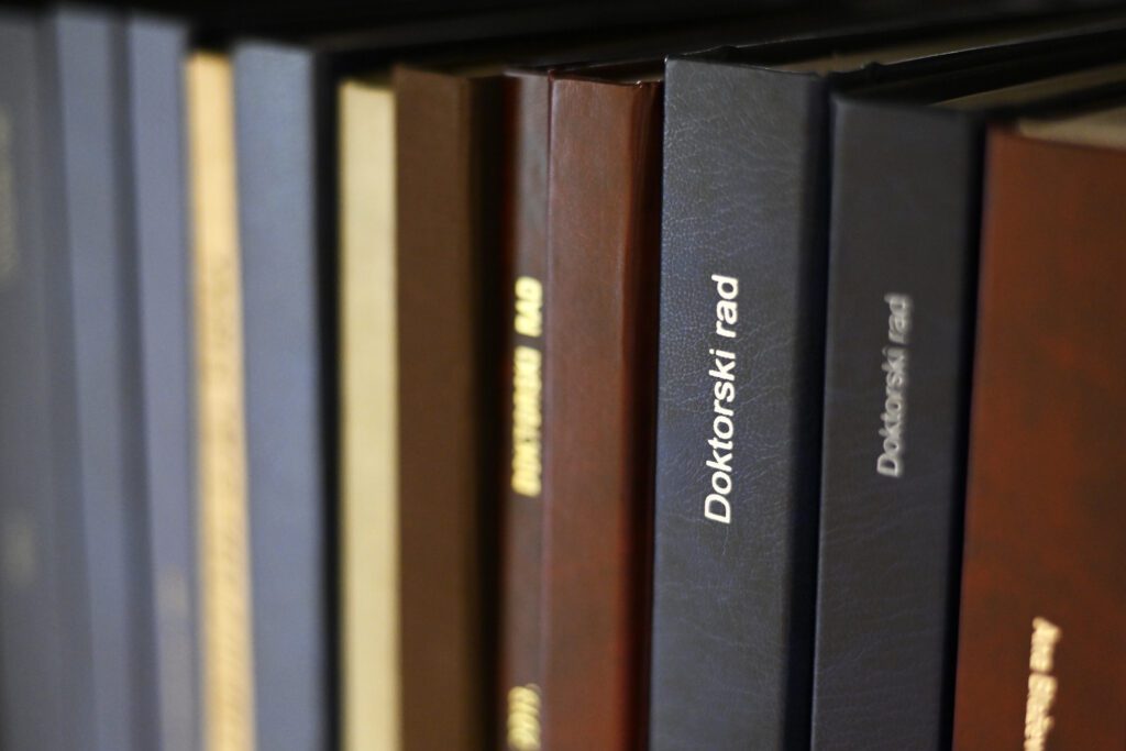 Several doctoral and other theses on open access shelves in the NSK Doctoral and Master's Theses Collection's reading room.