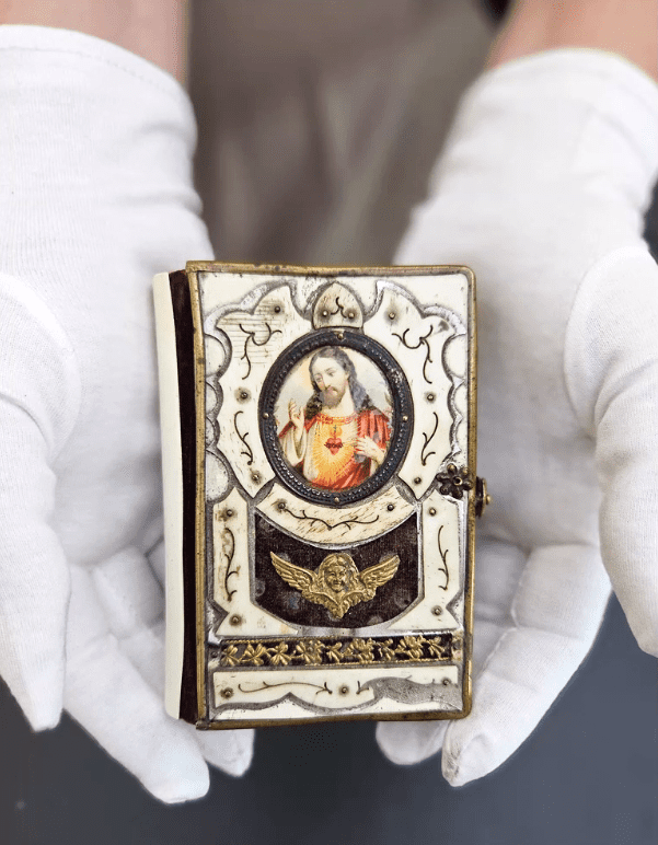 A miniature prayer book in a librarian’s hands.